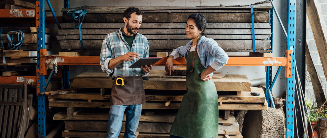 Two workers in aprons in a lumber shed