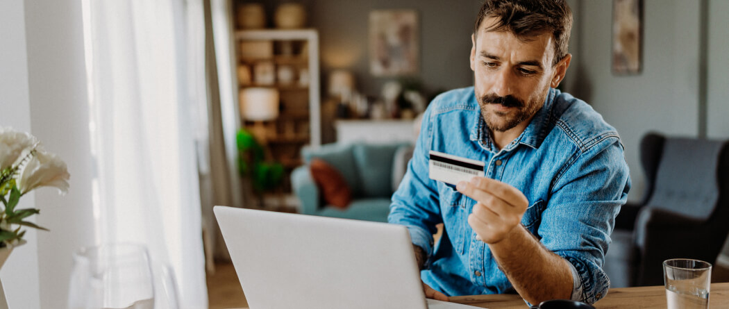 man holding a credit card and using a laptop