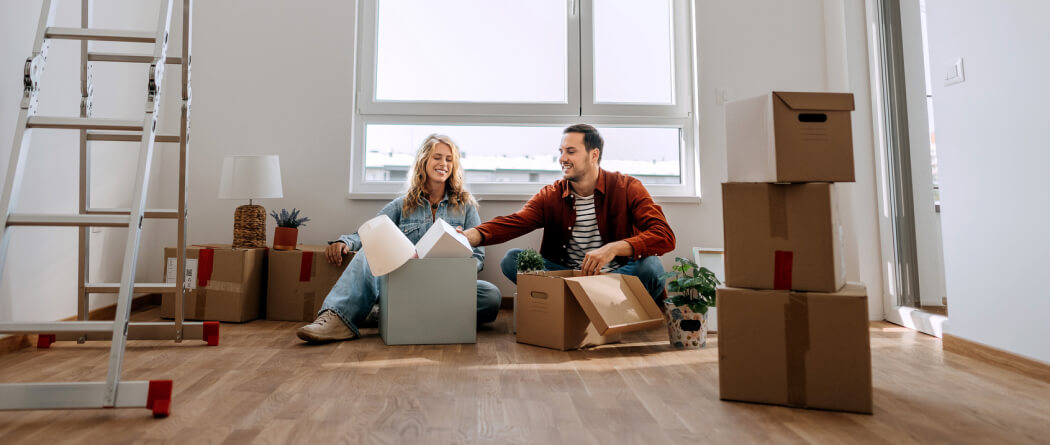 young couple unpacking boxes in an empty room 